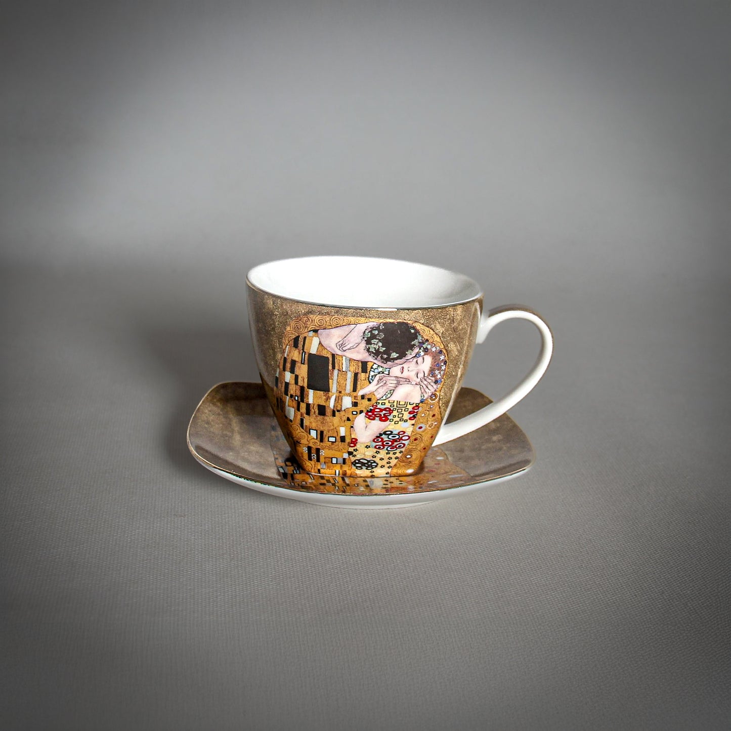 front and side view of Gustav Klimt The Kiss Cup and a matching saucer on a grey background
