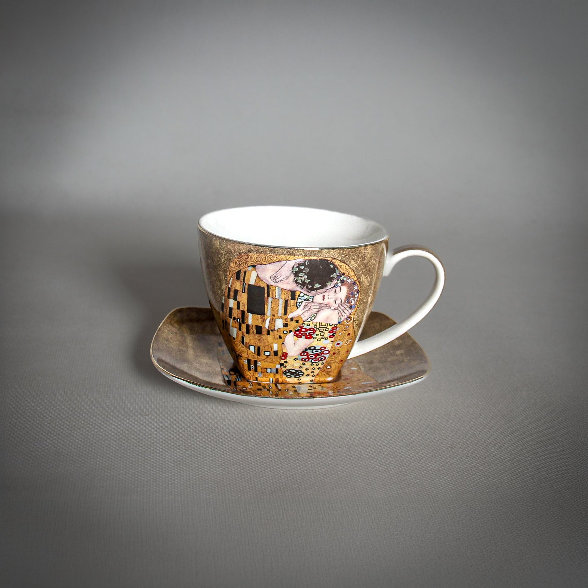 front and side view of Gustav Klimt The Kiss Cup and a matching saucer on a grey background